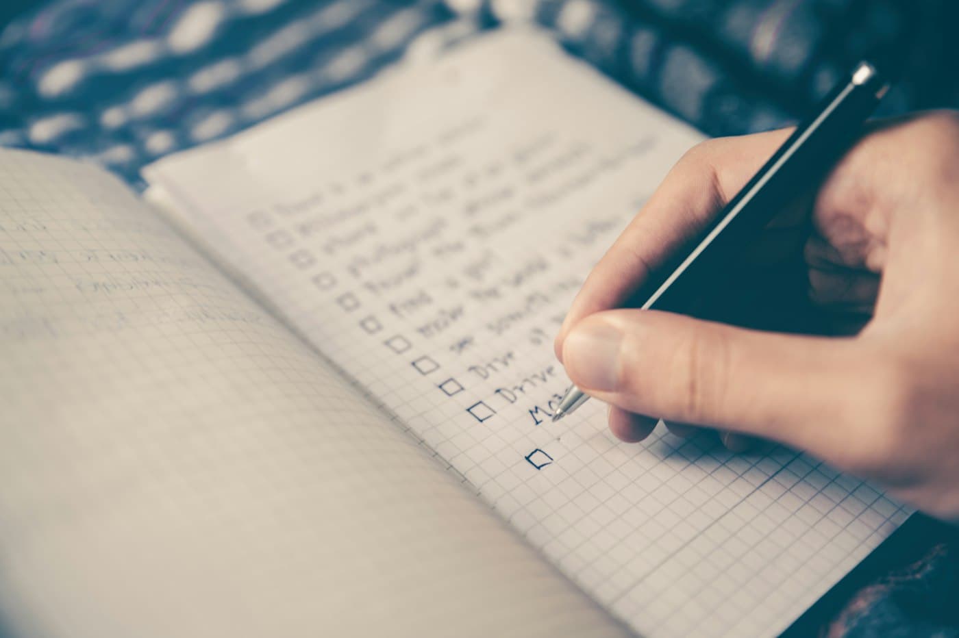 A hand ticking boxes on a handwritten checklist