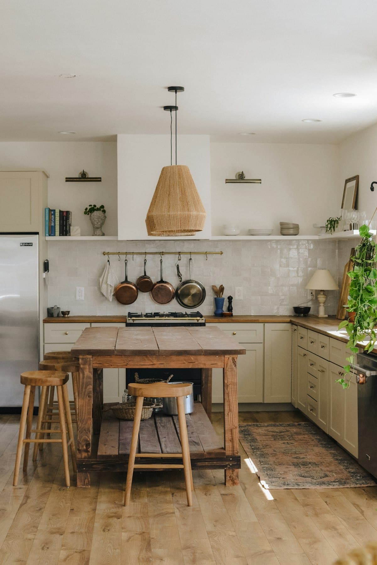 A warm, tidy kitchen with a wooden table and hanging pans